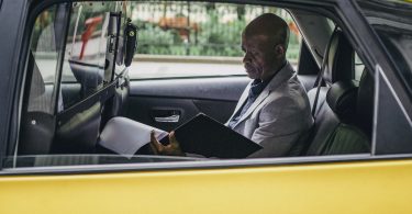 Pensive black entrepreneur examining important report in car