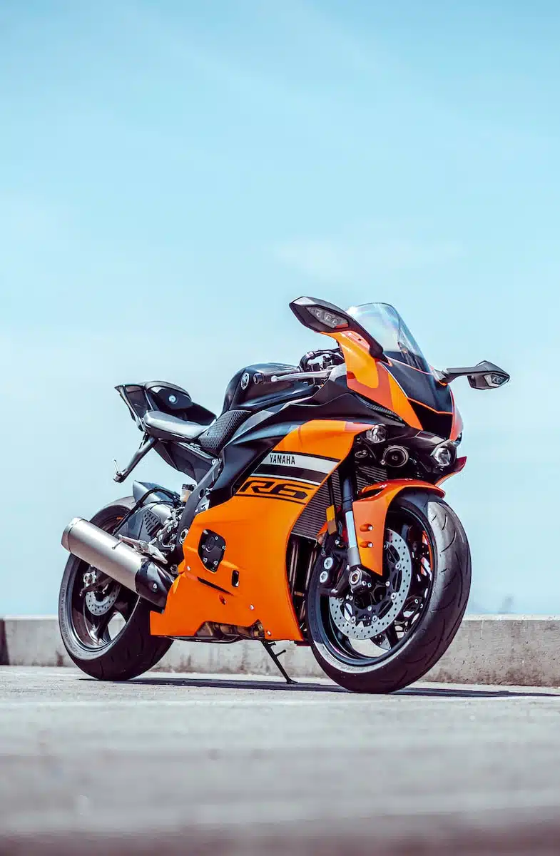 orange and black sports bike parked on gray concrete pavement during daytime