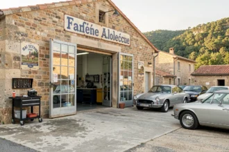 Vue panoramique d'un garage automobile typique en Ardèche avec façade en pierre et collines verdoyantes en arrière-plan