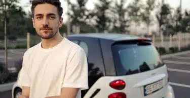 man in white crew neck t-shirt standing beside white car during daytime